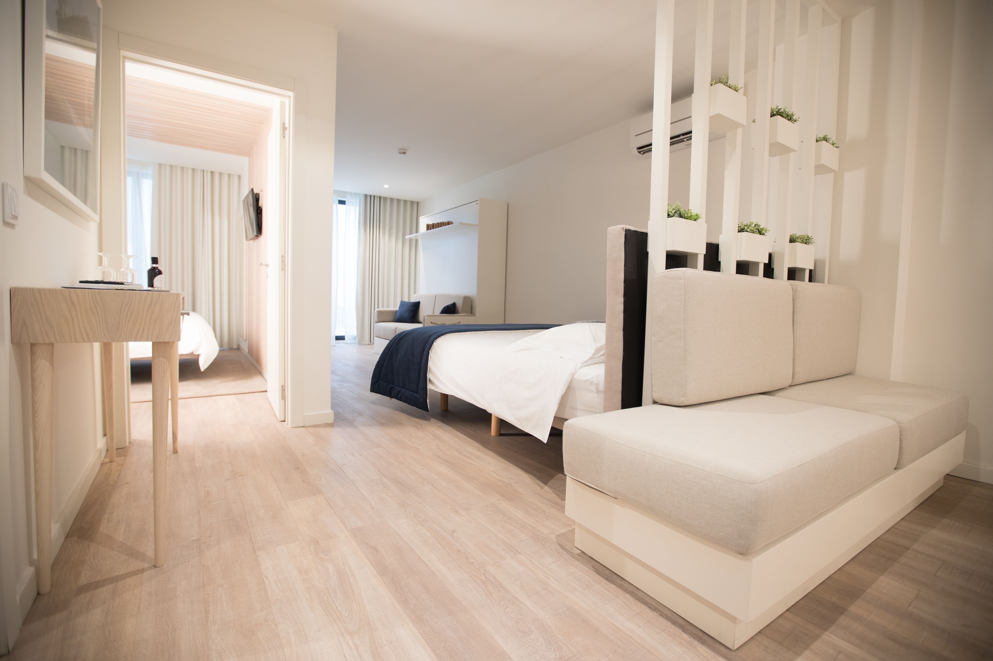 Una moderna camera d'albergo con un letto, un divano, una scrivania e uno specchio.