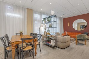 A modern living room with a dining area, featuring a wooden dining table, chairs, a sofa, and a coffee table. - ASKA Heiðmörk (Kópavogur)