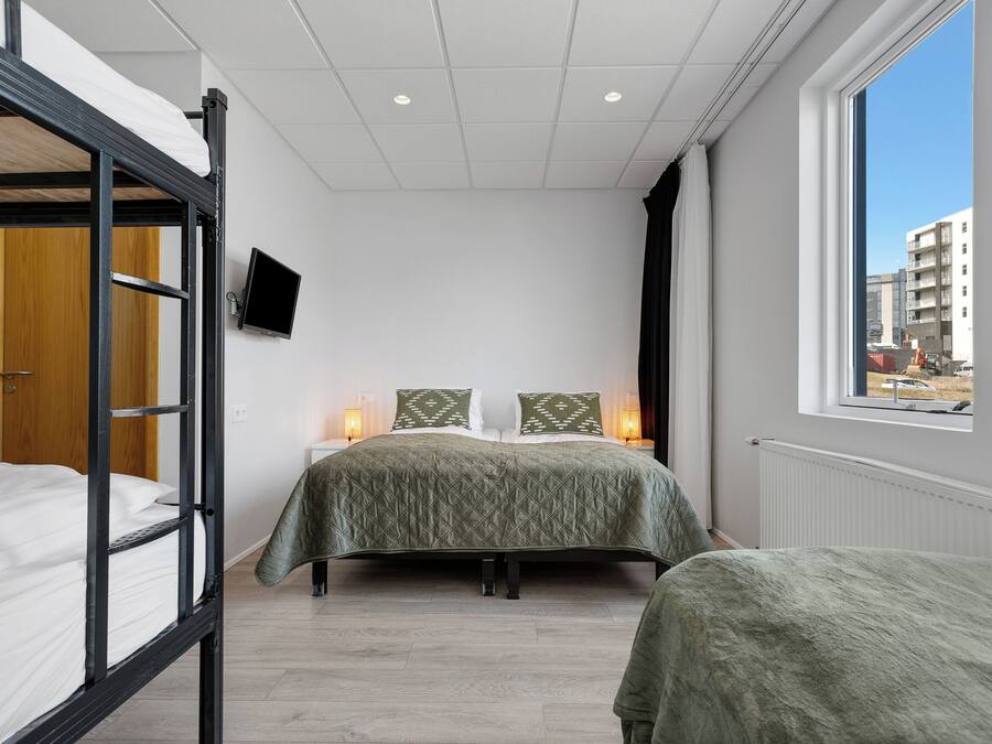 Una camera da letto con un letto a castello, un letto singolo, una grande finestra con vista, una TV a schermo piatto e un termosifone.