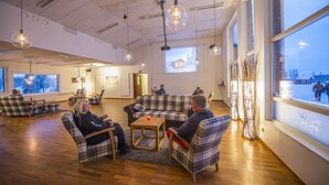 Un espacio interior amplio con diversas opciones de asiento, una pantalla de proyección y grandes ventanales con vistas al exterior.