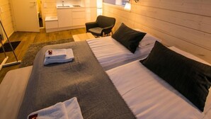 Una habitación de hotel moderna con una cama grande, un escritorio pequeño, una silla y una kitchenette.