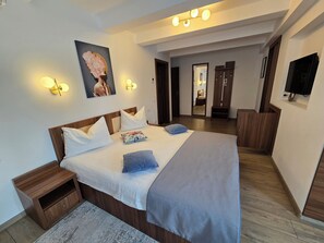 A modern hotel room with a large bed, wooden headboard, and a flat-screen TV mounted on the wall. - Pensiunea Transilvania (Sibiu)