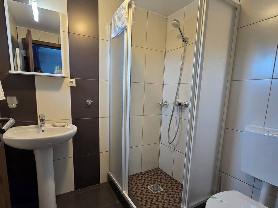 A bathroom with a shower, sink, and toilet.