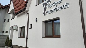 A building with a sign reading "Pensionia Transilvania" and a window with a curtain. - Pensiunea Transilvania (Sibiu)