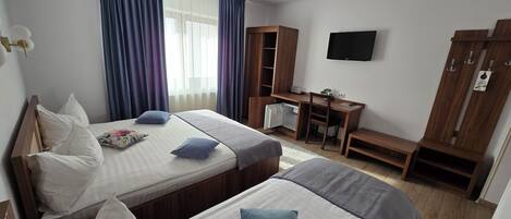 A hotel room with two beds, a desk, a TV, and a wardrobe.