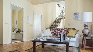 Sala de estar com sofá, mesa de centro e escada.