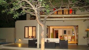 A modern house with a dining area, kitchen, and outdoor seating. - BushGlam Luxury Holiday Home (Hoedspruit)