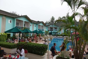 A poolside area with multiple umbrellas, lounge chairs, and a swimming pool. - Wusum Hotel (Makeni)