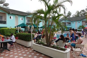 A poolside area with outdoor seating, palm trees, and a swimming pool. - Wusum Hotel (Makeni)
