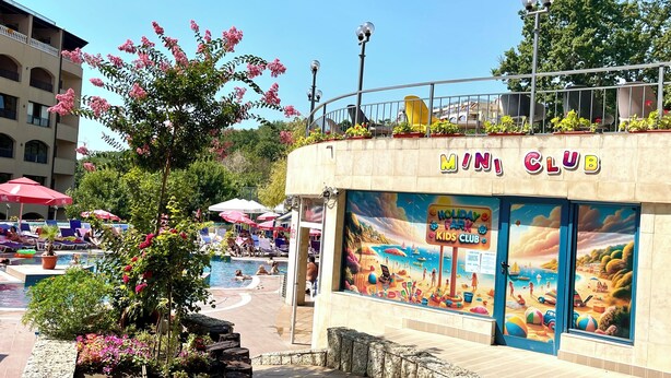 Un bâtiment portant l’inscription « MINI CLUB » et orné d’une fresque colorée représentant une scène de plage.