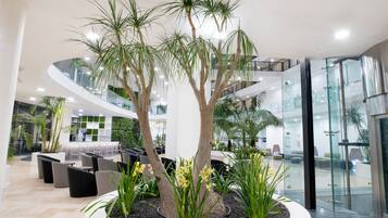 Eine moderne Lobby mit einem zentralen Atrium, Sitzbereichen und Glaswänden.