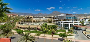 A hotel with multiple floors, a central courtyard, and a mountain backdrop. - GF Victoria (Adeje)