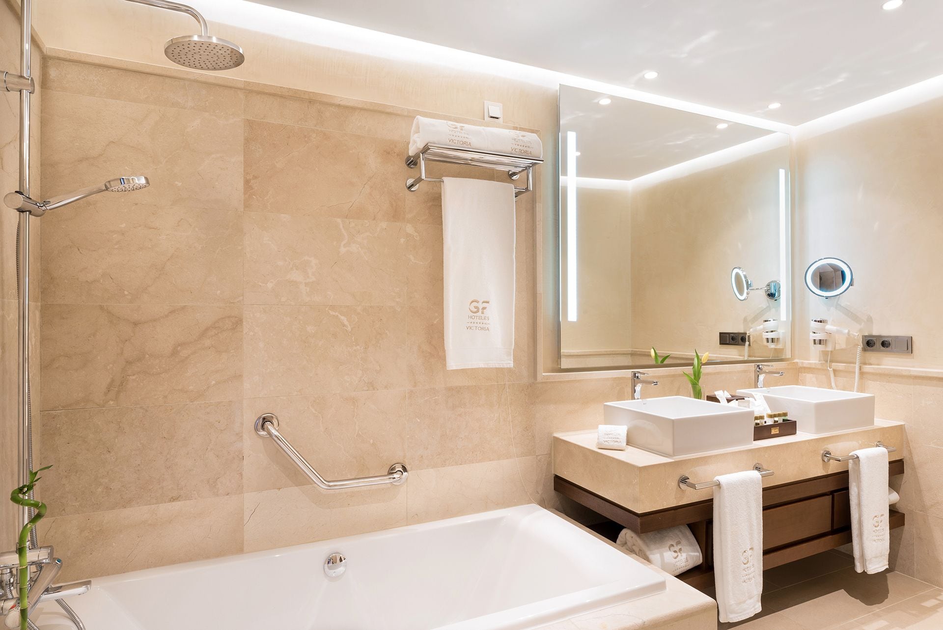 Une salle de bain moderne avec une baignoire, deux lavabos, une douche et un meuble-lavabo.