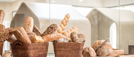 Wicker baskets filled with various types of bread displayed in a modern setting with geometric architectural elements.