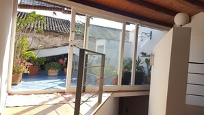 A room with a large window overlooking a courtyard with potted plants and a tiled roof.