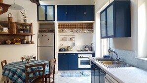 A compact kitchen with blue cabinets, a refrigerator, a stove, and a sink.