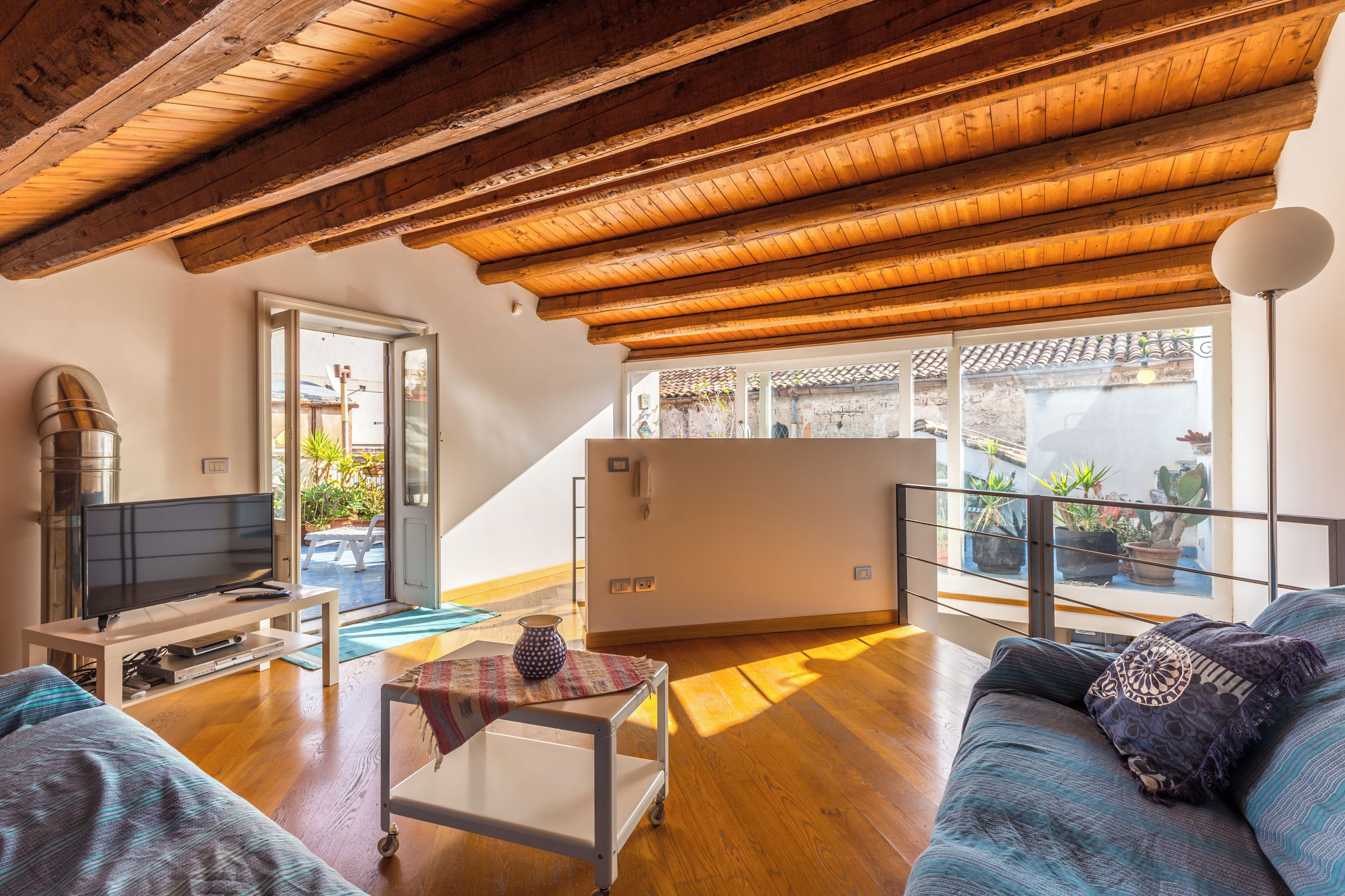 A spacious living area with a wooden ceiling, a television, a sofa, and a coffee table.