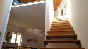 A wooden staircase in a room with a high ceiling and a window.