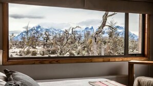Un dormitorio con un ventanal grande con vistas a un paisaje montañoso.