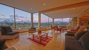 Un salón amplio con ventanas grandes, piso de madera y muebles modernos.