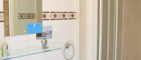Un baño con lavabo, espejo y ducha.