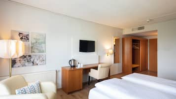 Una habitación de hotel con cama, escritorio, silla, televisor y armario.