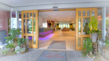 L'entrée de l'hôtel Michel Frankfurt Mainital comprend un comptoir d'accueil, un espace salon et des plantes en pot.