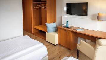 Une chambre d’hôtel avec deux lits, un bureau, une télévision et une armoire.