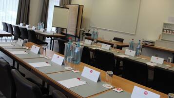 A conference room with long tables, nameplates, water bottles, and a whiteboard.