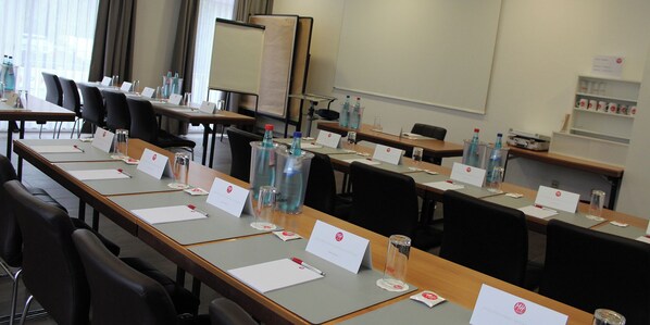 A conference room with long tables, nameplates, water bottles, and a whiteboard.