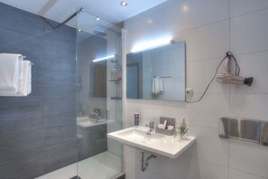 A modern bathroom with a glass-enclosed shower, a white sink, and a mirror. - ACHAT Hotel Frankfurt Maintal (Maintal)