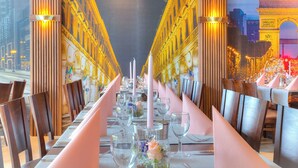 A long dining table set with pink napkins, clear glassware, and a centerpiece with flowers. - ACHAT Hotel Frankfurt Maintal (Maintal)