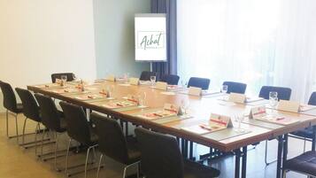 Une salle de conférence avec une longue table, des chaises, des porte-noms et des verres à vin.