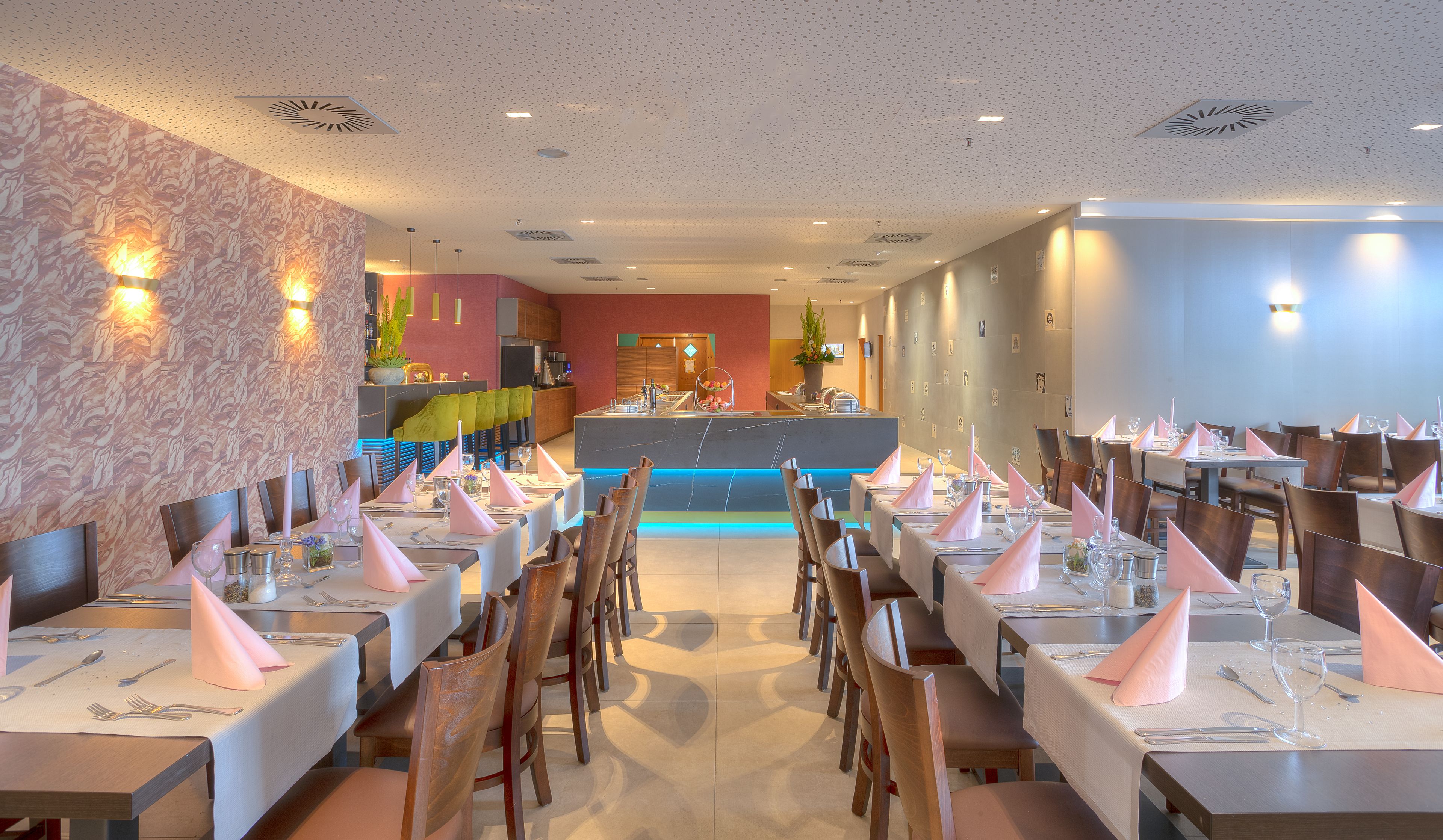 Ein Restaurant mit mehreren Esstischen, einer Theke mit einer Pflanze und einer Wand mit Muster.