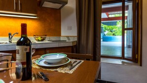 A dining area with a table set for two, a bottle of wine, and a bowl on the counter. - Merida Serviced Apartments (Mérida)