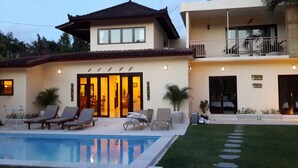 A two-story house with a swimming pool, lounge chairs, and a well-maintained lawn. - Aisha Family Villas-5Bedroom Private Pool (Seminyak)