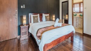 A bedroom with a wooden bed, a nightstand, a dresser, and a large mirror. - Aisha Family Villas-5Bedroom Private Pool (Seminyak)