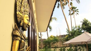 A golden statue at the entrance of a building, surrounded by palm trees and a covered outdoor area. - Aisha Family Villas-5Bedroom Private Pool (Seminyak)