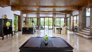 Una habitación amplia con techo de madera, ventanas grandes, un piano y una estatua.