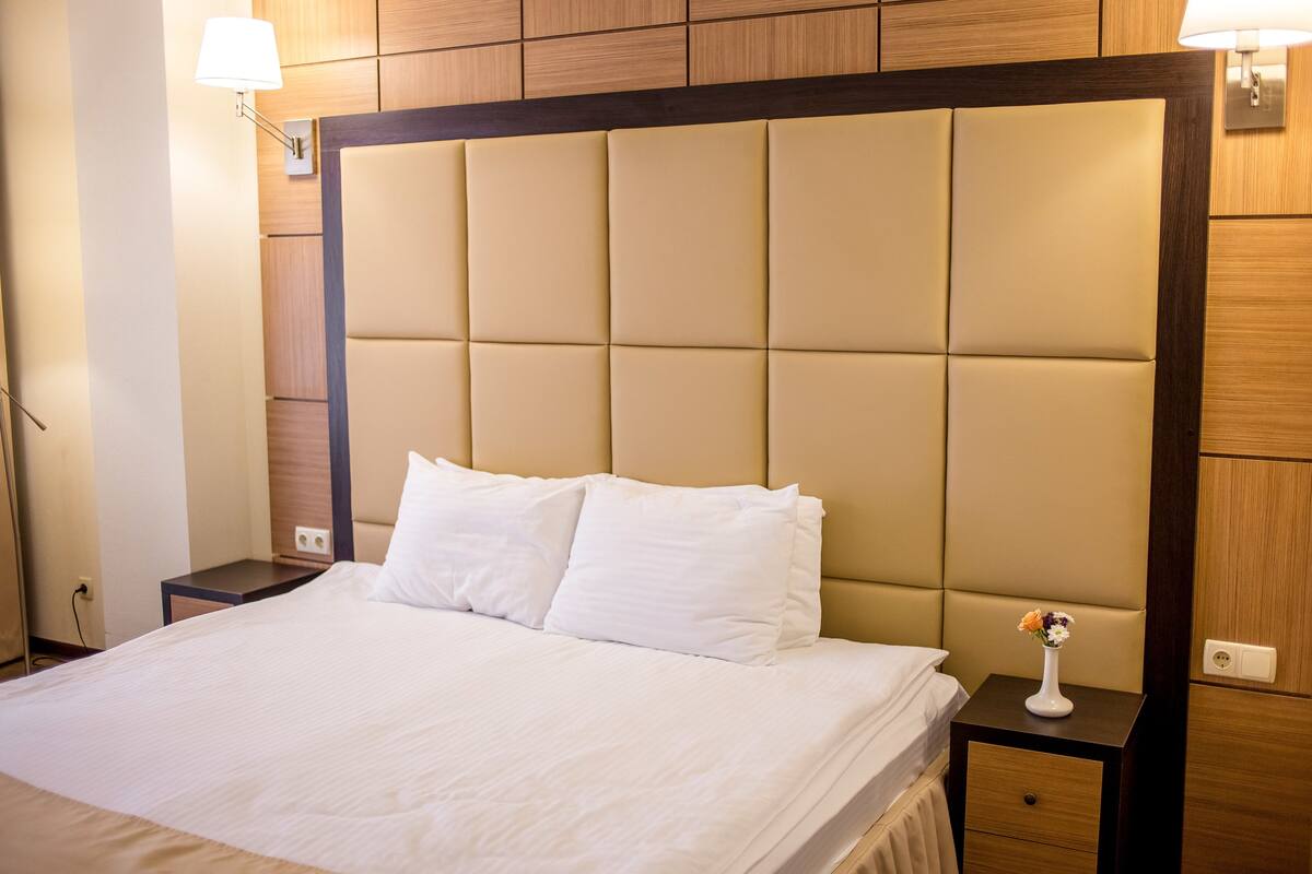 Habitación de hotel con una cama grande, una mesita de noche con lámpara y un aplique de pared.