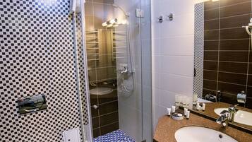 Un bagno moderno con doccia vetrata, un water bianco e due lavandini con piano in granito.