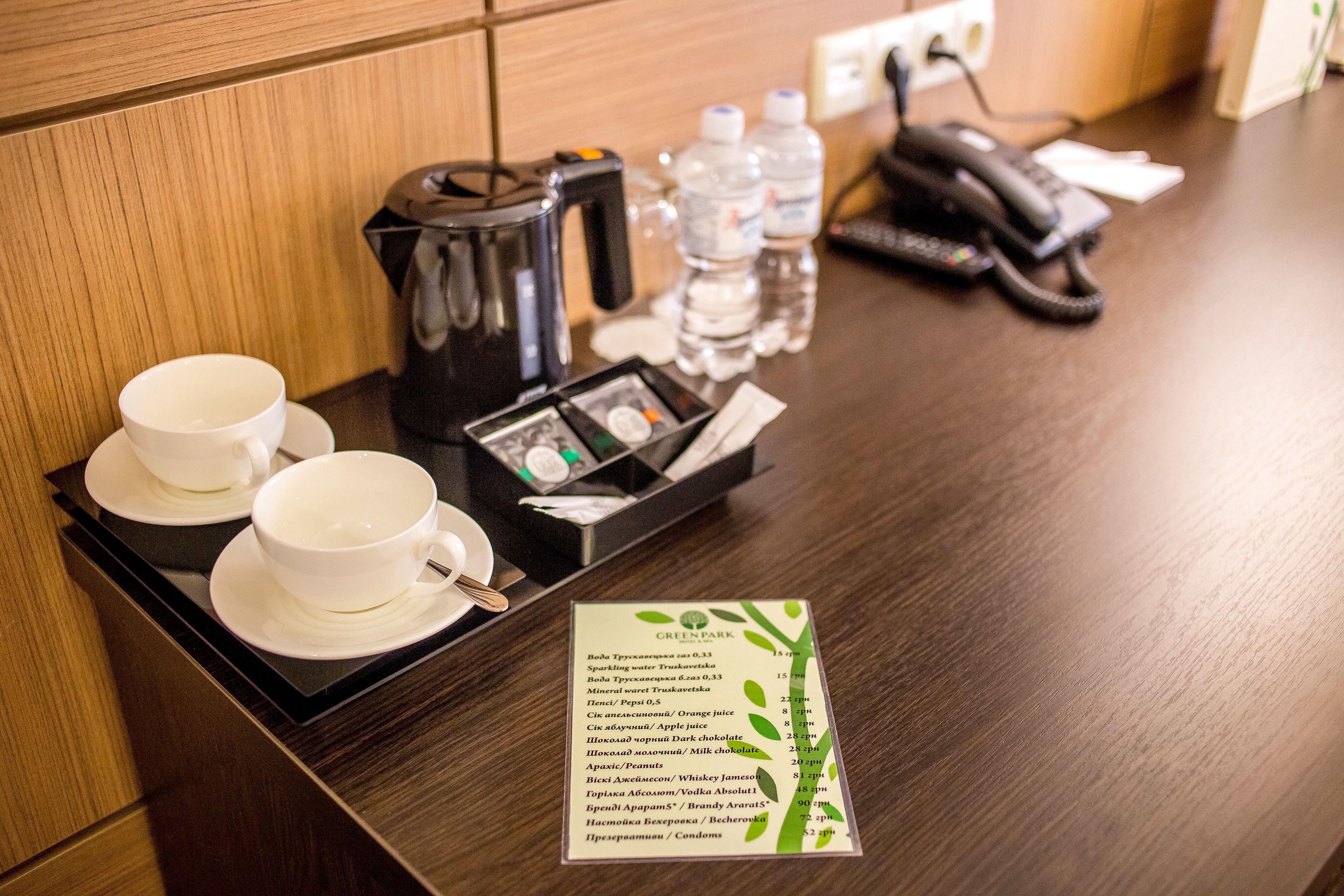 A hotel reception area with a coffee maker, water bottles, a phone, and a menu on the counter.