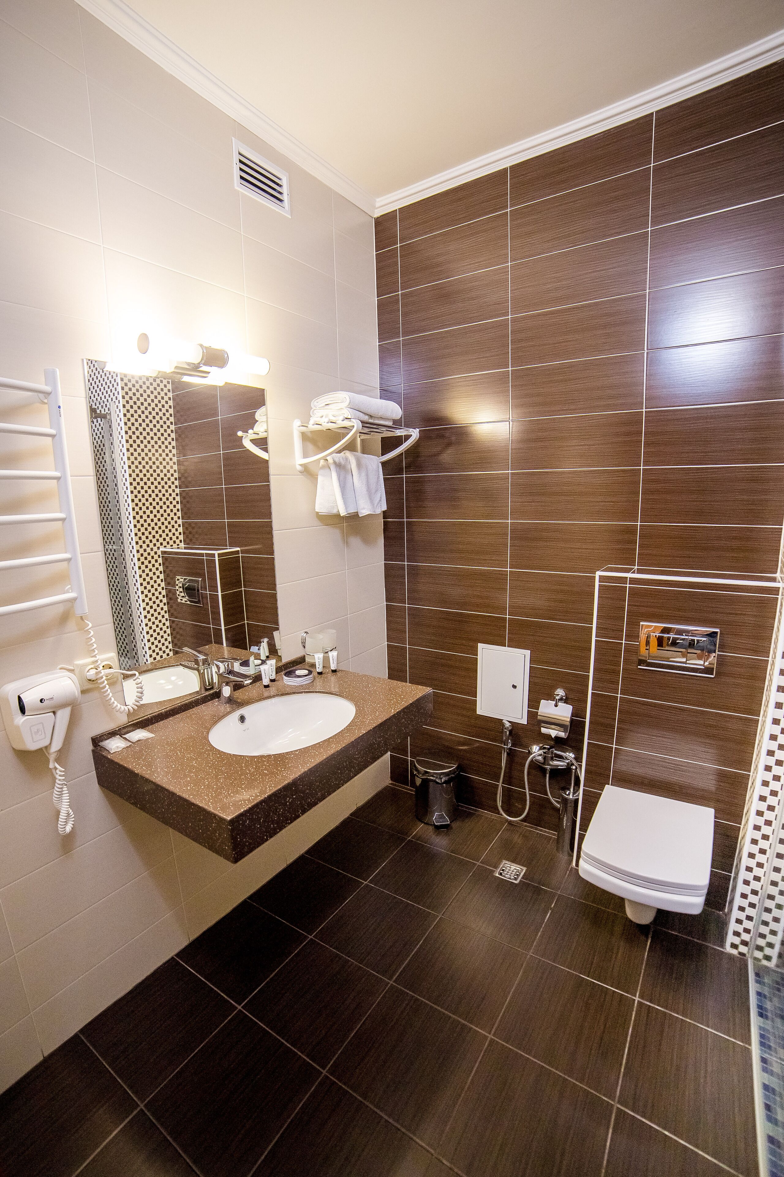 A modern bathroom with two sinks, a large mirror, a towel rack, and a shower area.