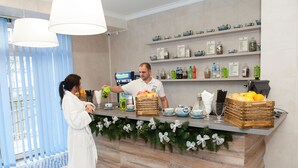 A hotel reception area with a wooden counter, a variety of bottles and containers on shelves, and a decorative garland. - Green Park Hotel (Truskavets)