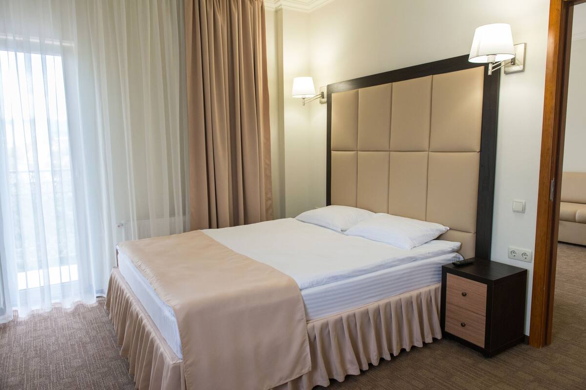 Una habitación de hotel con una cama grande, una mesita de noche y una lámpara de pared.