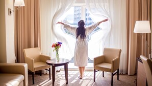 A room with a view through sheer curtains, a table with a vase of flowers, and two armchairs. - Green Park Hotel (Truskavets)