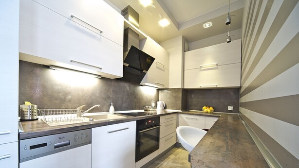 A modern kitchen with white cabinetry, a dishwasher, an oven, and a sink. - Rint - Centrum Nowy Świat (Bialystok)