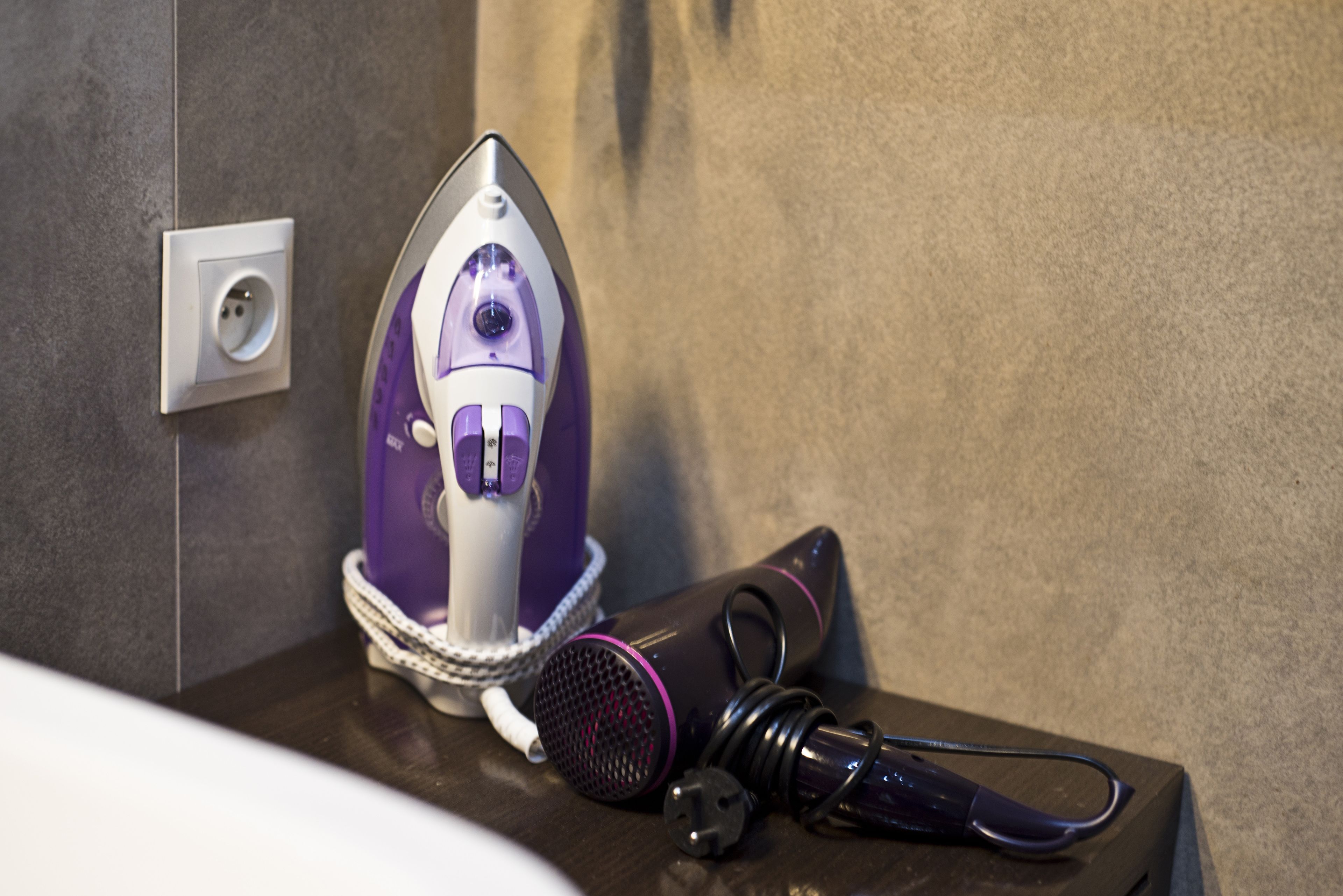 A bathroom with a modern design, featuring a built-in hairdryer and a compact mirror.