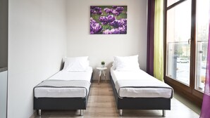 A room with two beds, a small table with a plant, and a large window with curtains. - Rint - Centrum Nowy Świat (Bialystok)