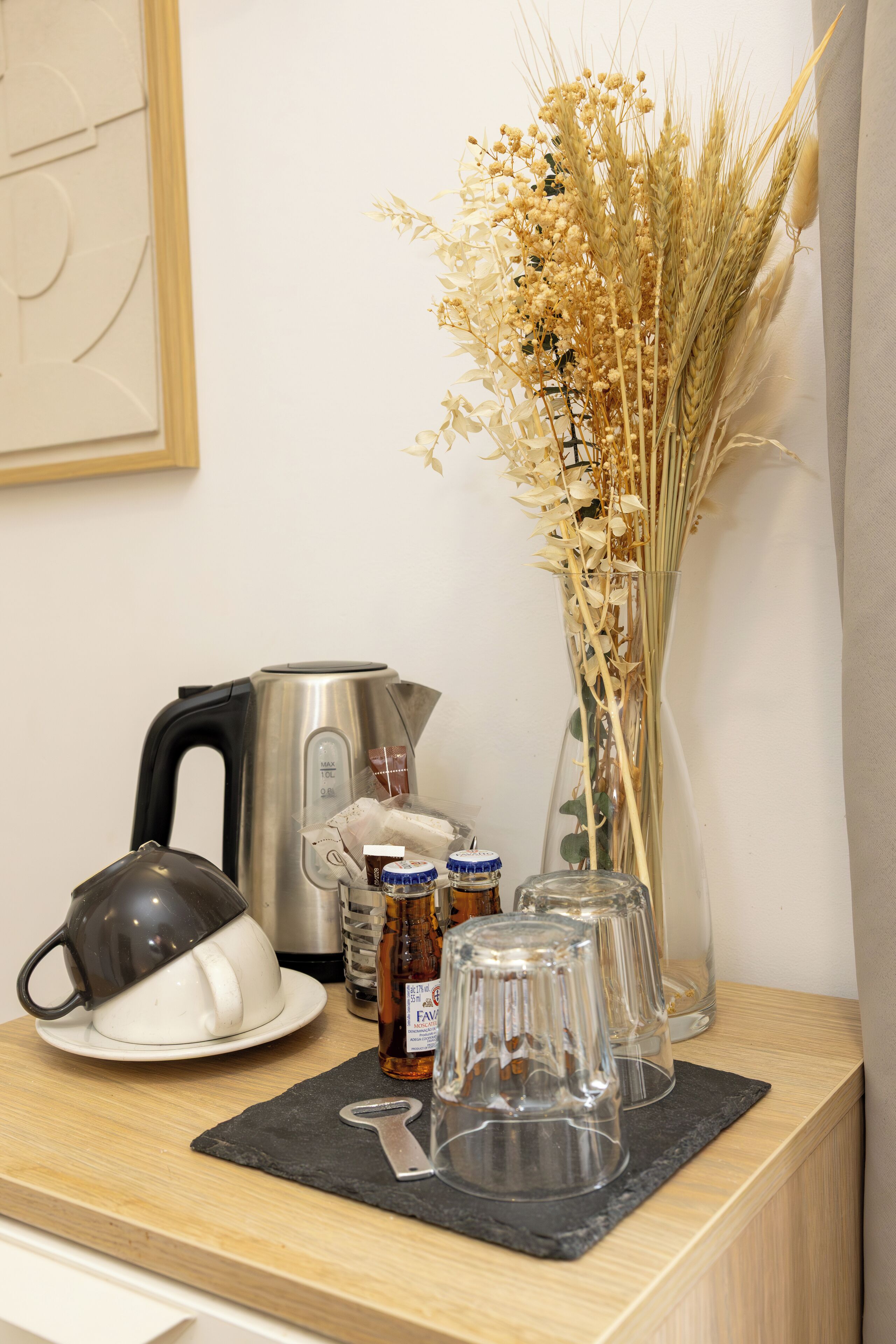 Eine Küchenarbeitsplatte mit einem Wasserkocher, einer Vase mit getrockneten Blumen und einer Honigflasche.
